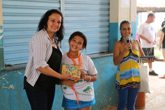 Viviane Suares do micro-projeto Biblioteca Folhas da Vida entrega livros a diretora Sheila Luiza no ato de celebrar a escola Jonathan Pontes Athias como parceira do Rios de Encontro.