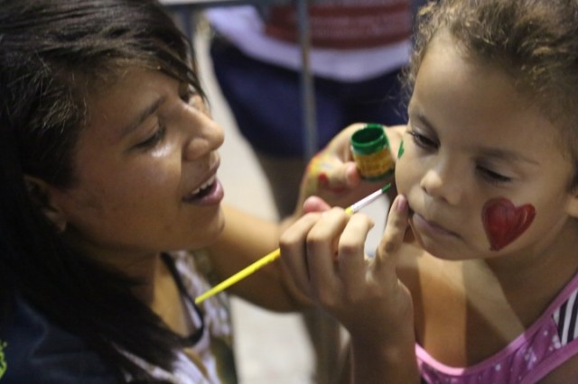 Carol, uma dos coordenadores de Folhas da Vida, ministra a oficina de pintura de rosto durante a primeira noite do festival, na Mendonça Cultural.